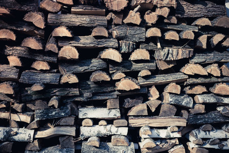 Neatly stacked firewood for heating a rural house in winter. Toned wooden background for design.