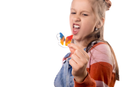 Portrait of little girl with orthodontics appliance isolated on white background.
