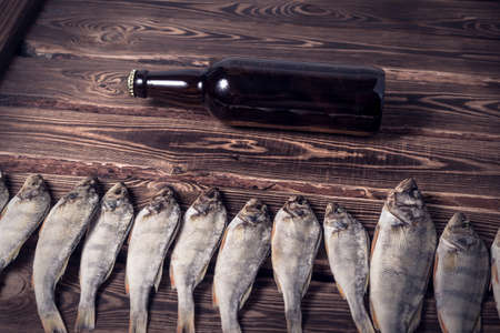 Brown bottle with beer and dried fish on a wooden table. Studio photo.の写真素材