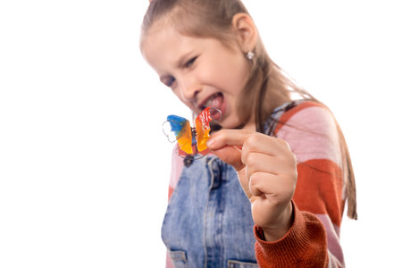 Portrait of little girl with orthodontics appliance isolated on white background.