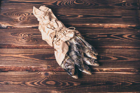 Beautiful dried fish in a paper bag on a wooden table. Studio photo.の写真素材