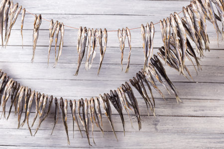 Small dry fish on a rope on a wooden background. Studio photo.の写真素材