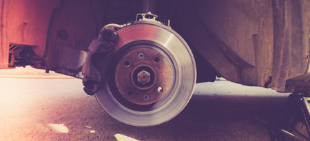 Photo of an old rusty brake disc on a car. The process of replacing brake pads on a car. Photo in...