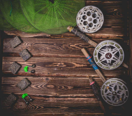 Old rarity bottom fishing reels on a wooden background. Bell, fish tank and makuha cubes. Studio photo with place for textの写真素材