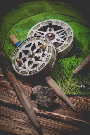 Old rarity bottom fishing reels on a wooden background. Bell, fish tank and makuha cubes. Studio photo.の写真素材