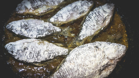 The process of frying fresh crucian carp in a pan with hot oil. Cooking fish at home.