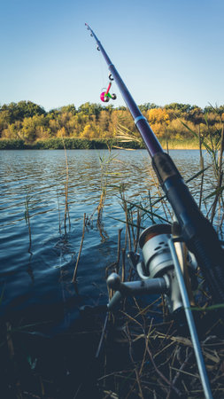 Fishing rod with a bell on the lake in the autumn. Toned photo with the vignetting.