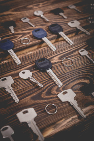 Studio photo of different keys on a wooden background. Photo in the old style with vignetting.