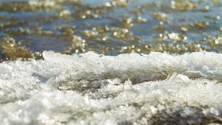 The first ice on the bank of a muddy reservoir in winter. Background for design. Photo taken with a...