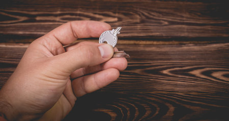 The man holds in his hand a small light broken key. Studio photo on a wooden background.