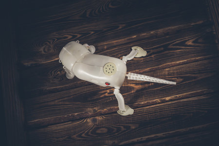 Plastic frame of a robot dog on a wooden background. Red button on the side. A studio photo with hard lighting.の写真素材