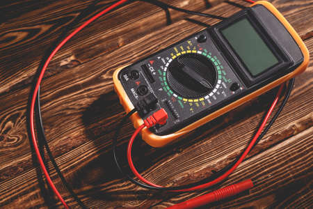 Multimeter and two test leads on a wooden background. A studio photo with hard lighting.の写真素材