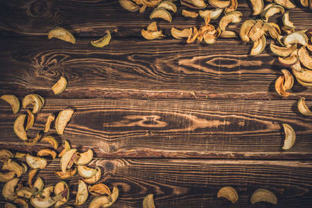 Slices of dried apples on a wooden background. A studio photo with hard lighting.の写真素材