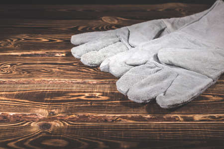 White leather welder gloves on a wooden background. A studio photo with hard lighting.の写真素材