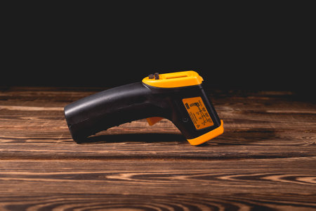 Yellow-black pyrometer on a wooden background. A device for non-contact temperature measurement. Studio photo.の写真素材