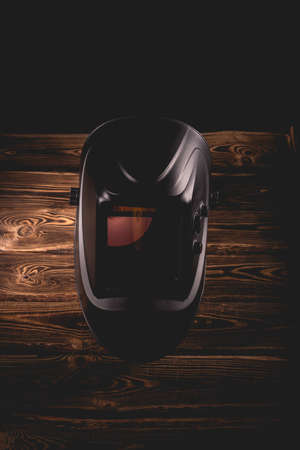 Black welding mask on a wooden background. A studio photo with hard lighting.の写真素材