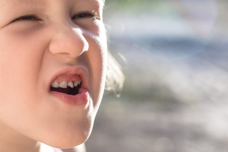 Cute little baby opened her mouth and showed wobbly baby toothの写真素材