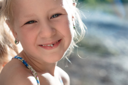Portrait of a little girl with a wobbly baby tooth.の写真素材