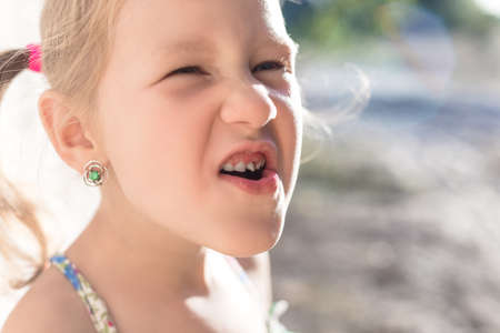 Cute little baby opened her mouth and showed wobbly baby toothの写真素材