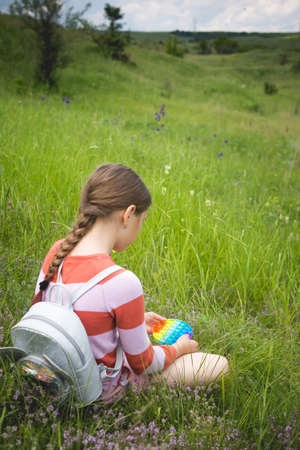 A little cute girl is sitting on the grass - anti stress toy.の写真素材