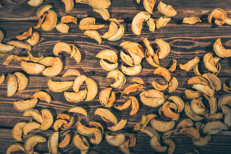 Slices of dried apples on a wooden background. A studio photo with hard lighting.の写真素材
