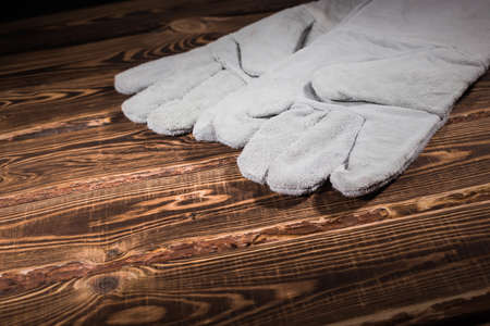 White leather welder gloves on a wooden background. A studio photo with hard lighting.の写真素材