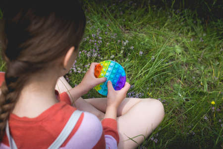 A little cute girl is sitting on the grass - antistress toy.の写真素材