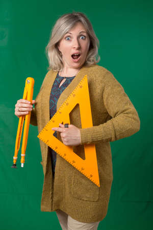 Adult woman posing with compasses and protractor. Photos on school subjects. Studio photo with chroma key background.の写真素材