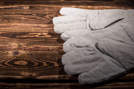 White leather welder gloves on a wooden background. A studio photo with hard lighting.の写真素材