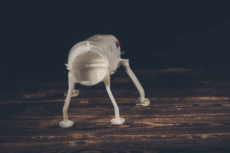 Plastic frame of a robot dog on a wooden background. Red button on the side. A studio photo with hard lighting.の写真素材
