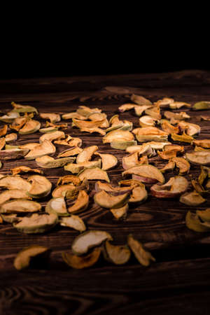 Slices of dried apples on a wooden background. A studio photo with hard lighting.の写真素材