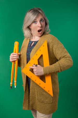 Adult woman posing with compasses and protractor. Photos on school subjects. Studio photo with chroma key background.の写真素材