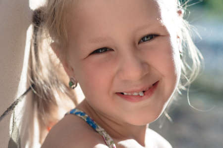 Portrait of a little girl with a wobbly baby tooth.の写真素材