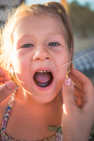 The process of removing a baby tooth using a thread.