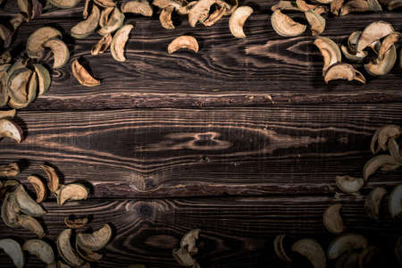 Slices of dried apples on a wooden background. A studio photo with hard lighting.の写真素材