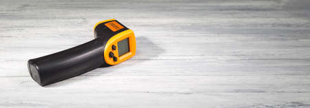 Yellow-black pyrometer on a wooden background. A device for non-contact temperature measurement. Studio photo.の写真素材