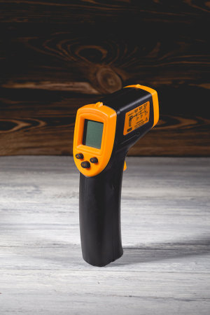 Yellow-black pyrometer on a wooden background. A device for non-contact temperature measurement. Studio photo.の写真素材