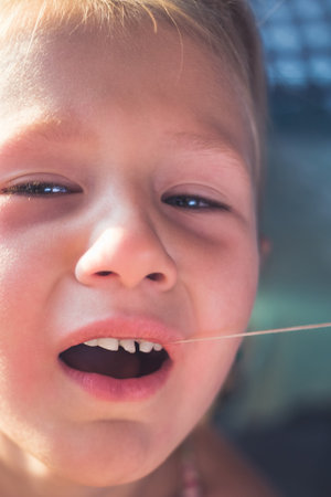 The process of removing a baby tooth using a thread.の写真素材