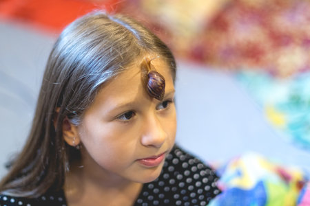 Little Achatina snail on the forehead of a cute little girlの写真素材