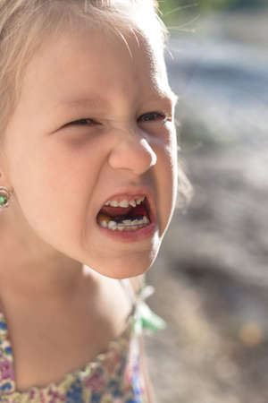 Cute little baby opened her mouth and showed wobbly baby toothの写真素材