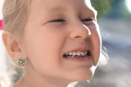 Portrait of a little girl with an outstretched milk tooth.の写真素材