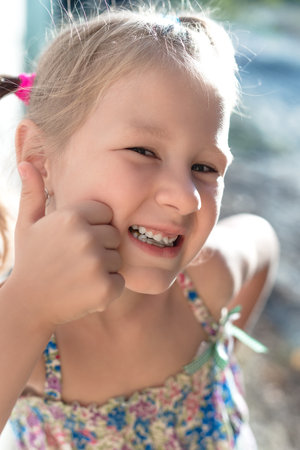 Portrait of a little girl with a wobbly baby tooth and a thumb up.の写真素材