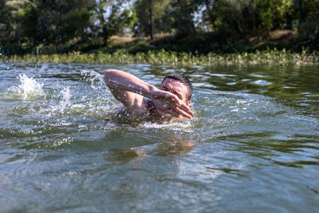 The young man swimming in the river.の写真素材