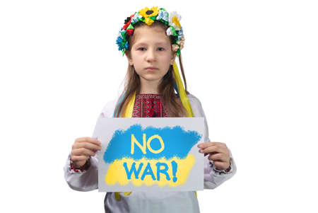 A little Ukrainian girl with tears in her eyes holds a sheet of paper with the inscription "No war!" in her hands. Studio photo on a white background.の写真素材