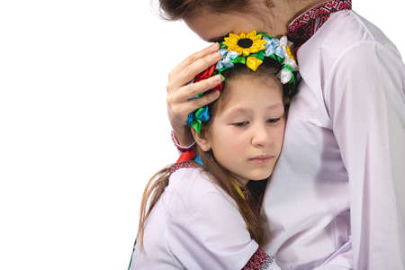 The mother hugs the child with tearful eyes. A child in Ukrainian national clothes. Studio photo on a white background.の写真素材