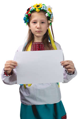 Little cute Ukrainian girl 11 years old posing in the studio on a white background. The child holds a blank white sheet in his hands. Preparation for the inscription.の写真素材