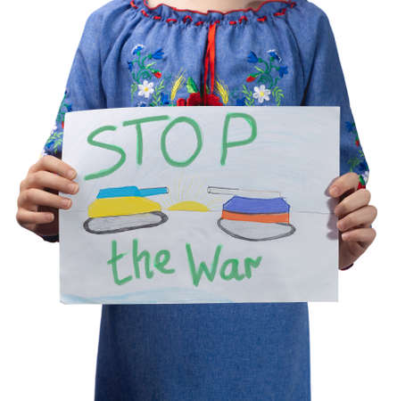 A little sad Ukrainian girl holds a drawing in her hands with the inscription "Stop the war". Studio photo on a white background.の写真素材