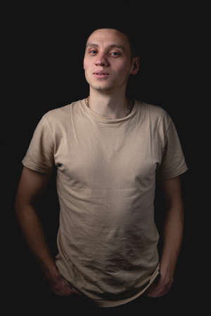 Handsome young man posing over black background. Studio photo with one light source. Smiling guy cheerfully posing in the studio.の写真素材