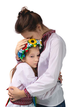 The mother hugs the child with tearful eyes. A child in Ukrainian national clothes. Studio photo on a white background.の写真素材