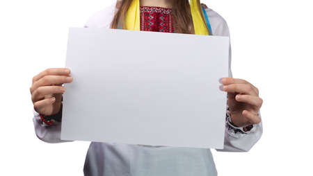 A little Little cute Ukrainian girl 11 years old posing in the studio on a white background. The child holds a blank white sheet in his hands. Preparation for the inscription. Studio photo isolated on white background.の写真素材